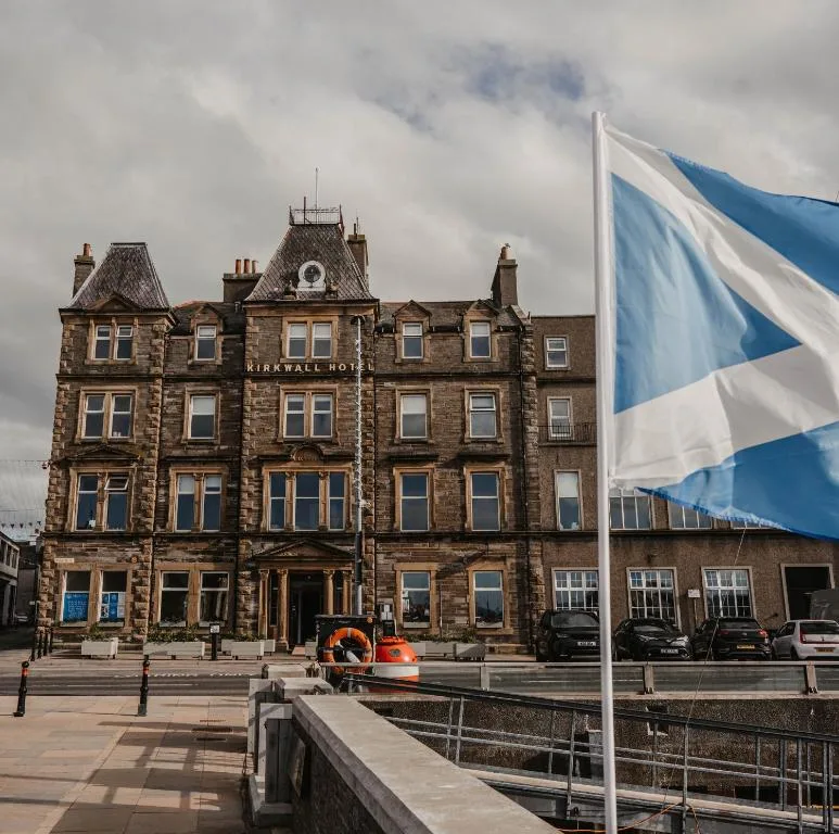 The Kirkwall Hotel on Harbour Street facing Kirkwall's working pier, a four-storey Victorian harbour-front hotel with the inter-island ferry visible at the quay