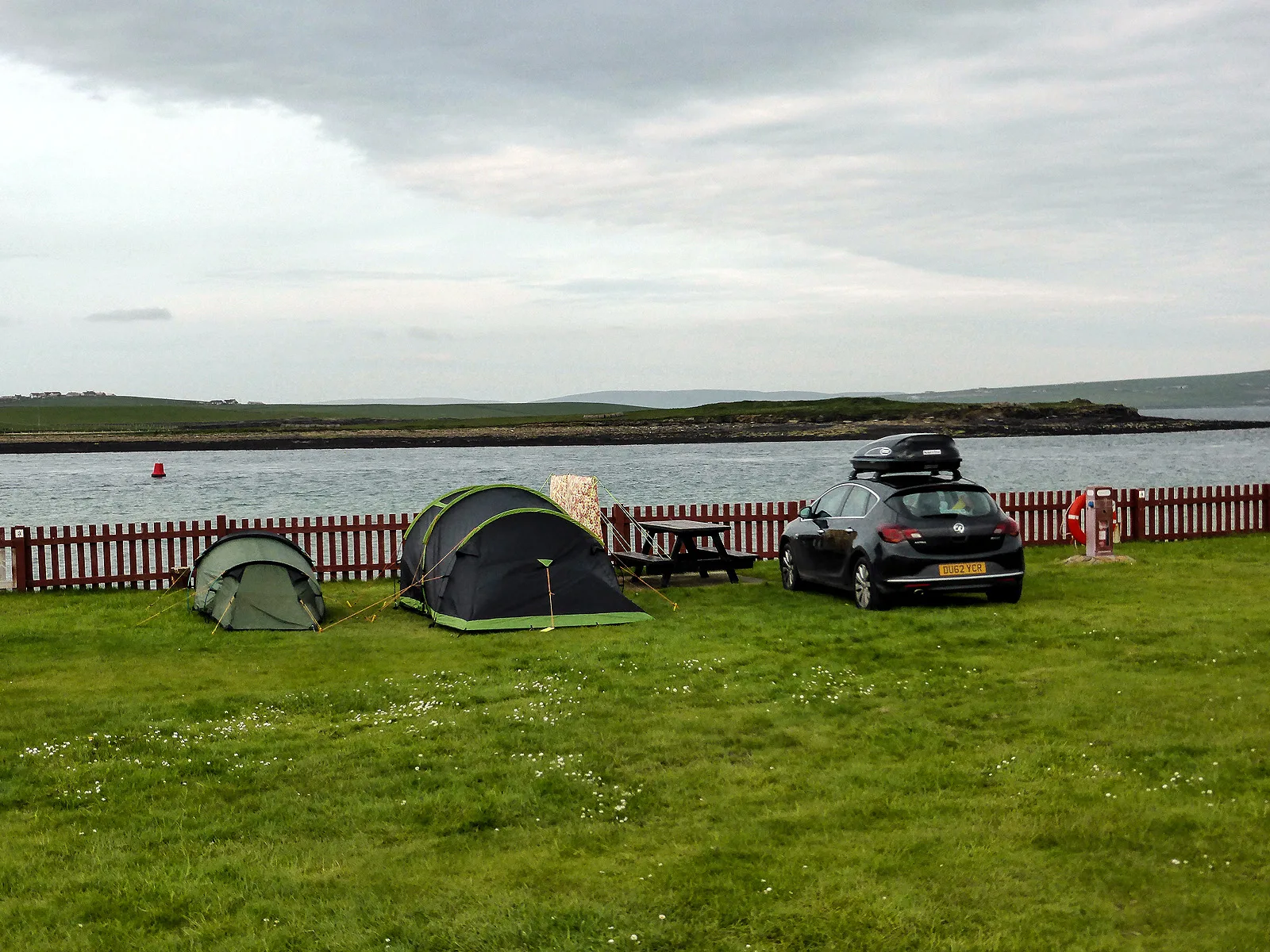 Tents pitched on the grass at the Point of Ness campsite in Stromness, Orkney, with the sea beyond