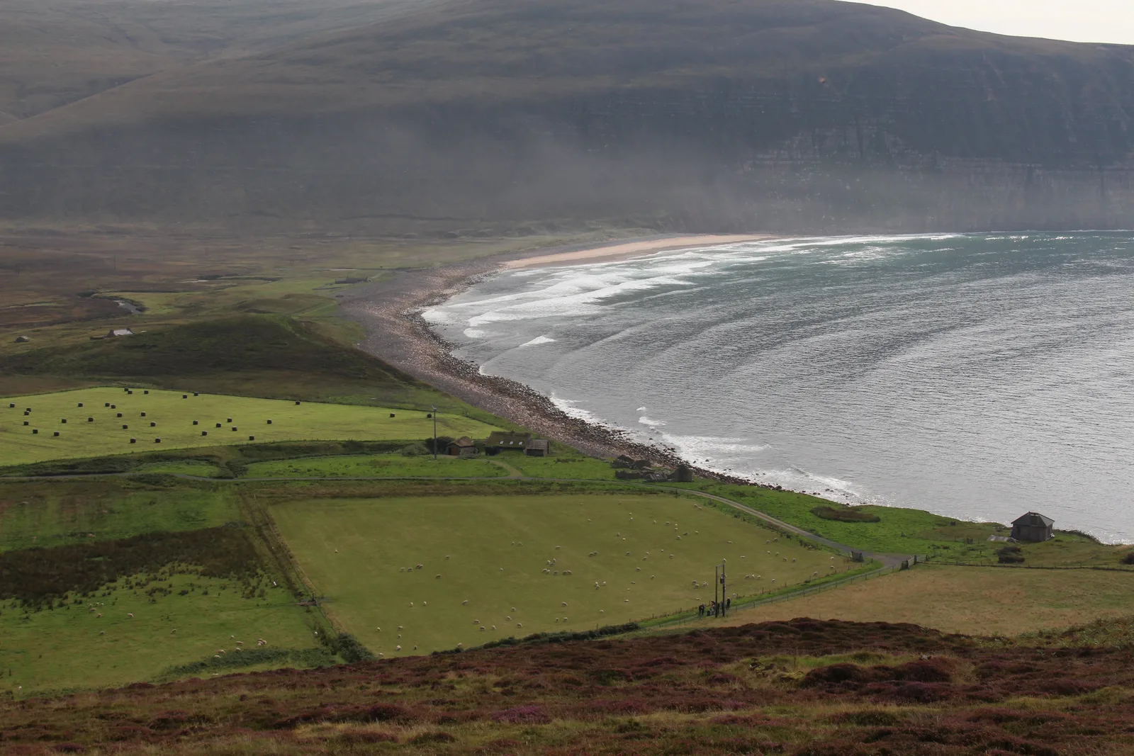 Rackwick Bay on Hoy, Orkney, a boulder and sand beach below steep hills and high cliffs