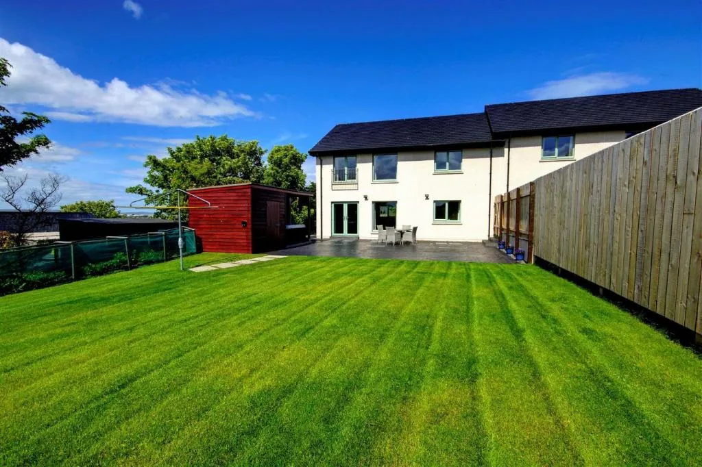Aurora Self-Catering, a modern three-bedroom holiday home on Upper Crantit Road outside Kirkwall, with the luxury hot tub set under a private gable and the lights of central Kirkwall in the middle distance