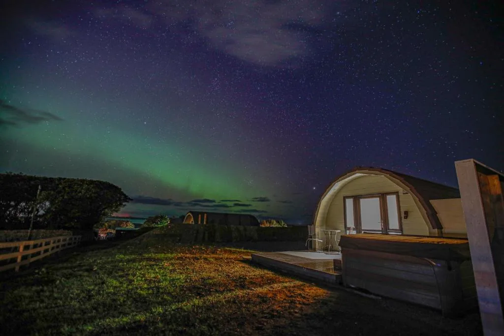 Berstane Lodges on the Berstane shore east of Kirkwall, a small cluster of contemporary timber lodges with private terraces and hot tubs facing the inner bay and the islands of Shapinsay and Helliar Holm