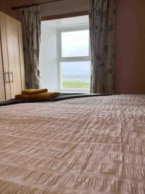 A bedroom at the Pierowall Bay house on Westray, Orkney, with the window framing Pierowall Bay and the village pier