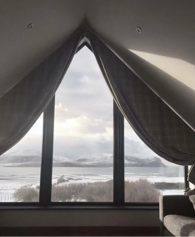 The sitting room of Switha, a luxury home in Stromness, with a large window framing the open sea and the hills of Hoy beyond