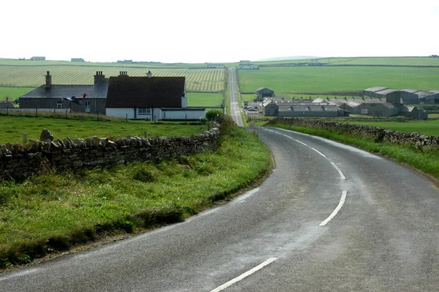 Swannay Farm buildings near Evie, Orkney — white-painted farm steading and outbuildings on green pastureland on the north-west Mainland, with low hills in the distance