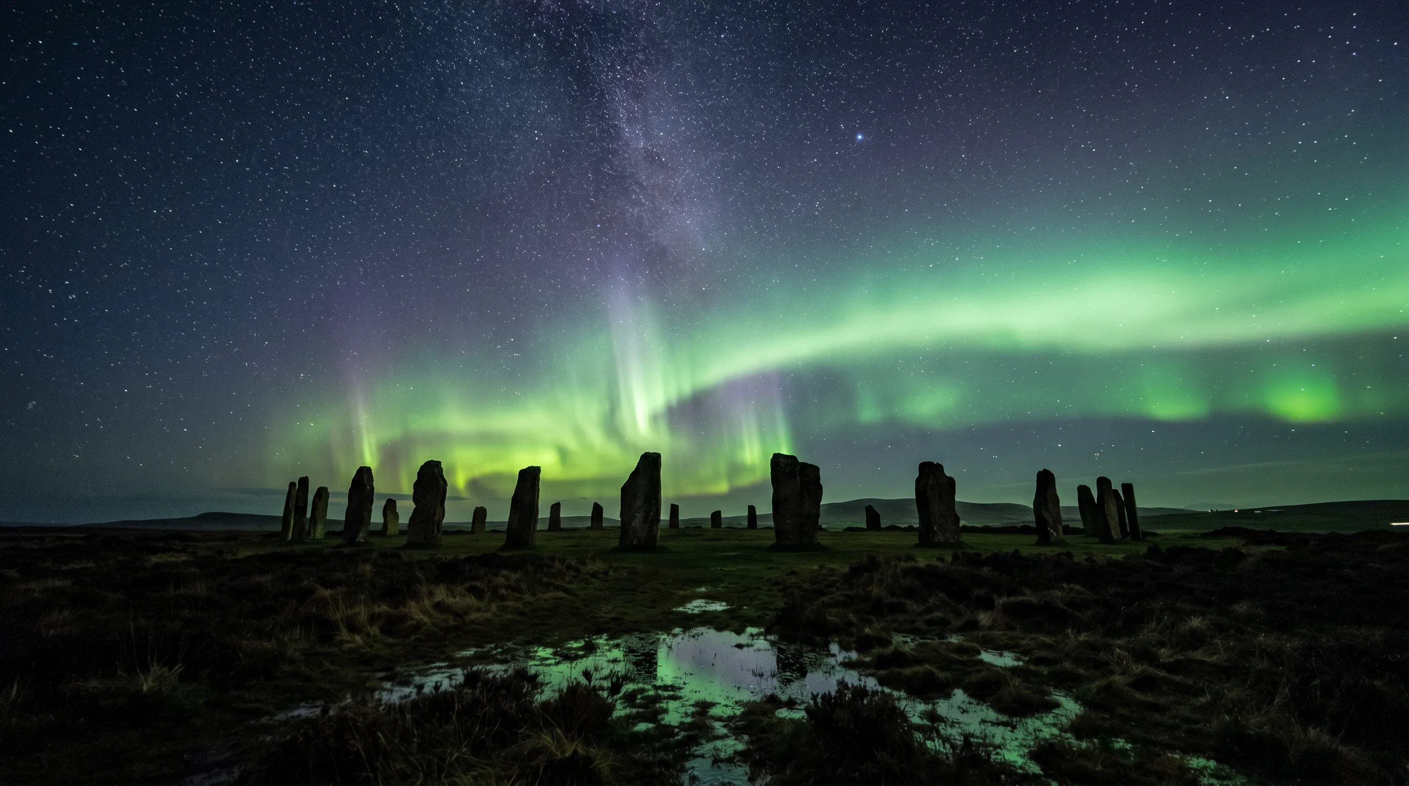 The Aurora Borealis glowing green over the Ring of Brodgar standing stones, Orkney, with the Milky Way overhead