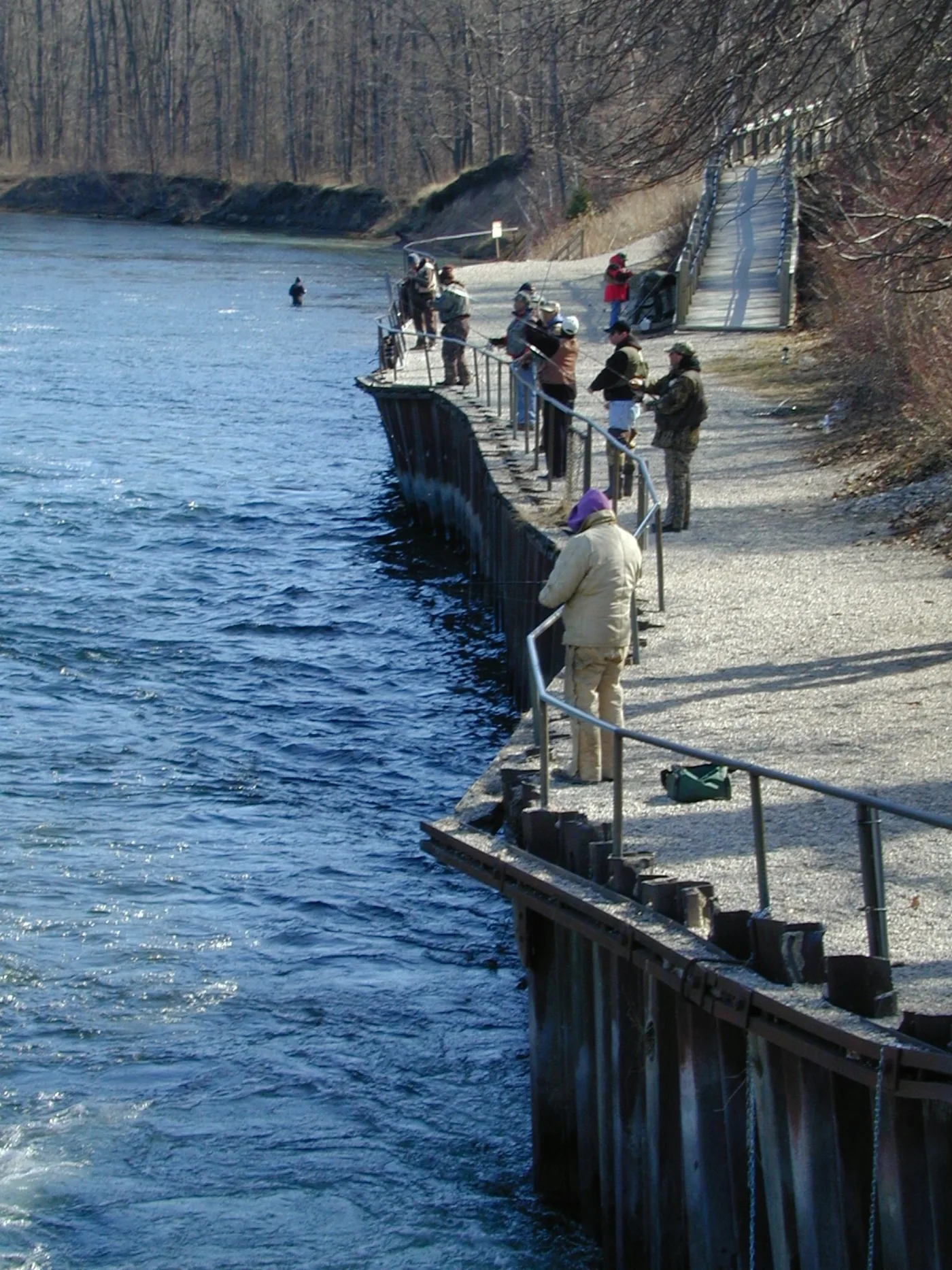 Anglers leaning on the railings to fish for steelhead below Foote Dam on the lower Au Sable River near Oscoda, Michigan