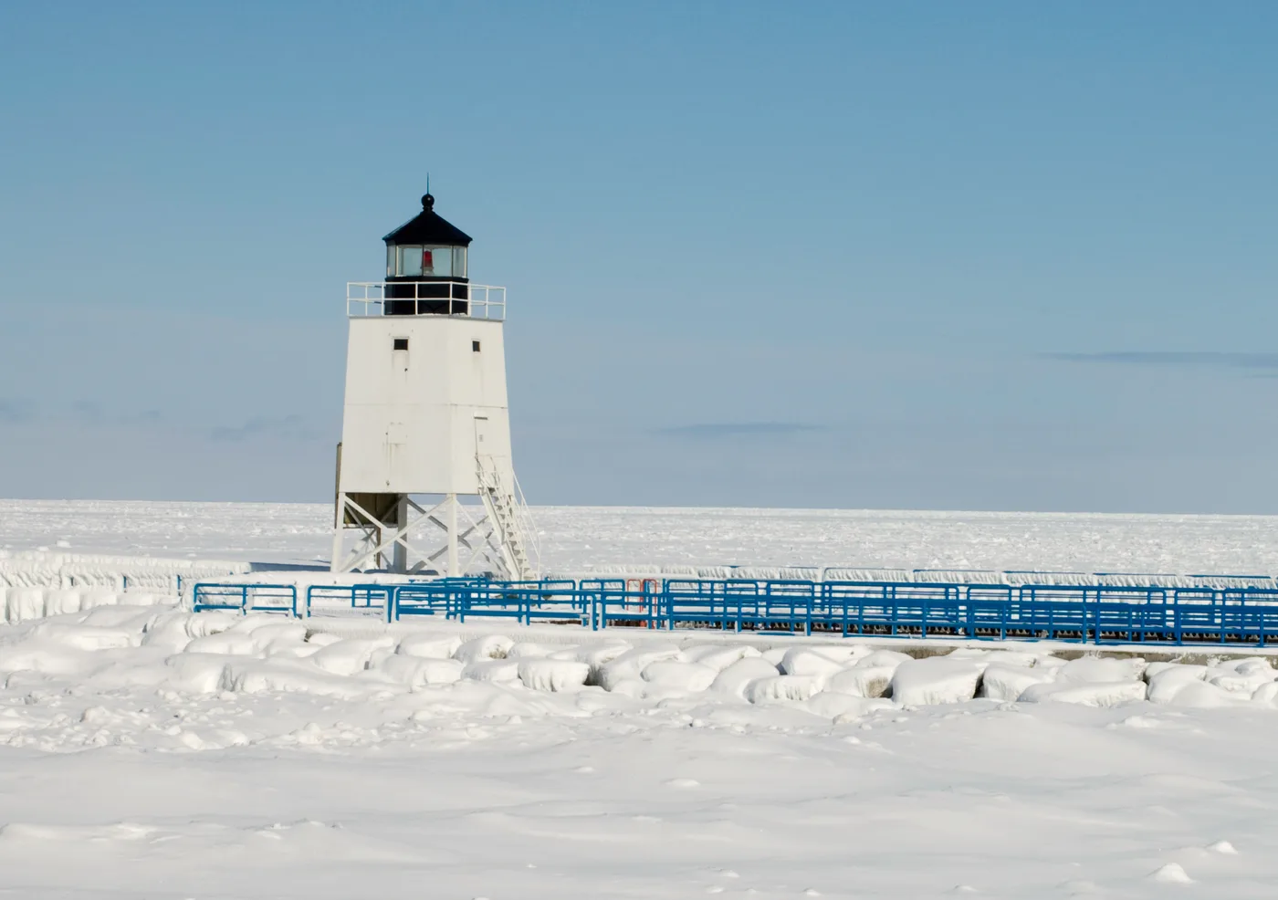 Charlevoix lighthouse on a frozen winter day, snow and ice covering the harbor, Northern Michigan