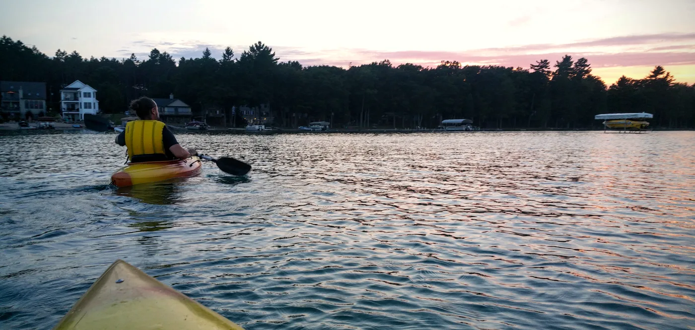 Kayaker paddling on Higgins Lake, Michigan on a calm summer day