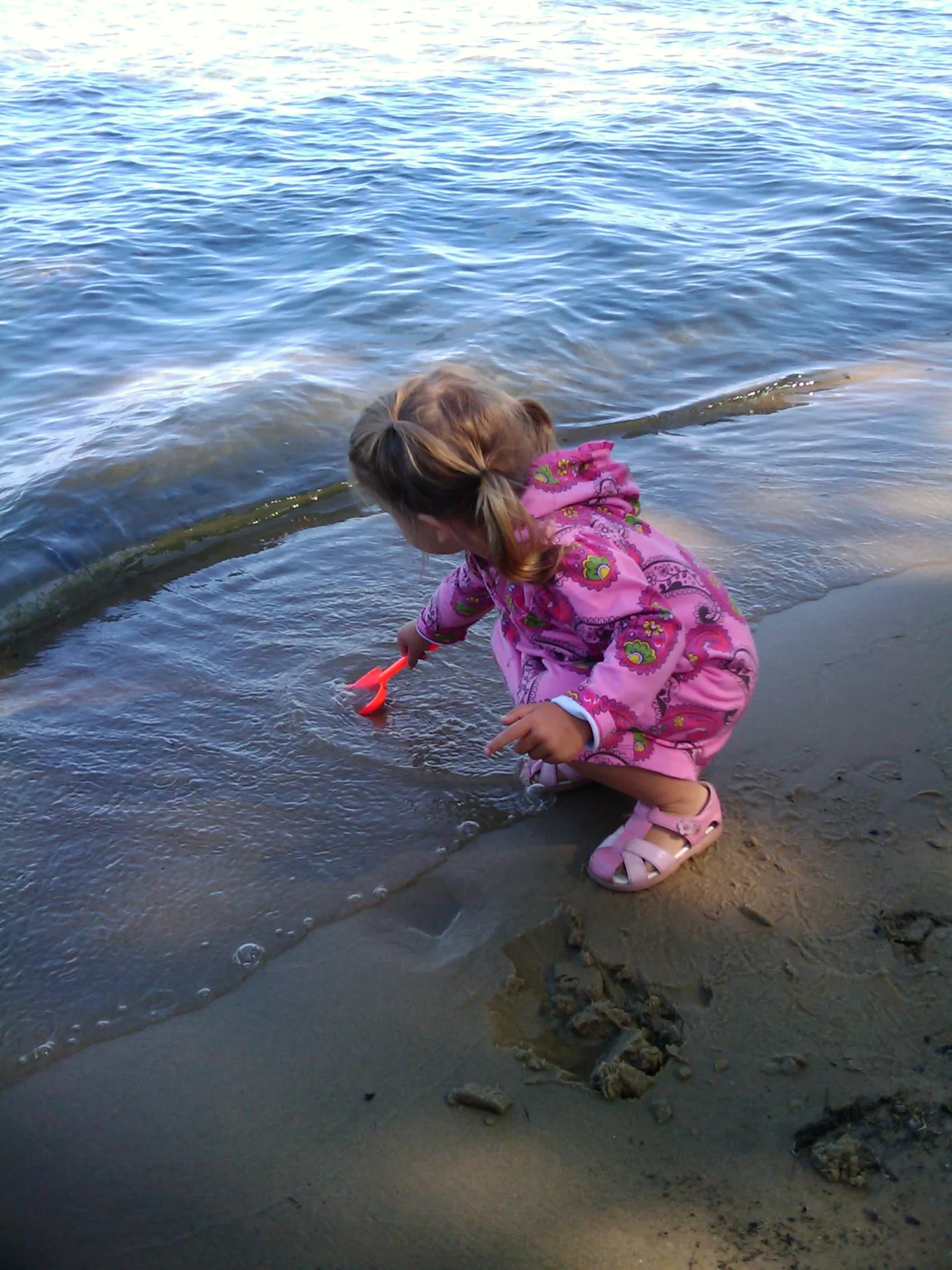 Young child playing at the water's edge at Higgins Lake, Michigan — calm clear water and sandy beach
