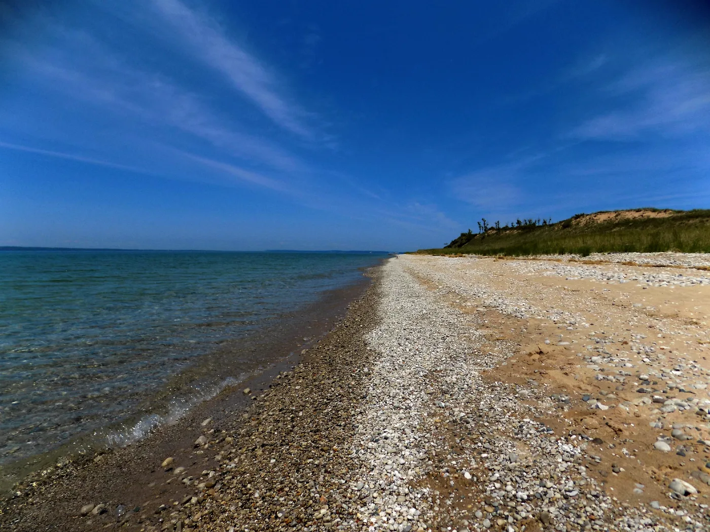 Sandy and pebbly shore of Lake Michigan near Sleeping Bear Dunes on a calm summer morning with turquoise water