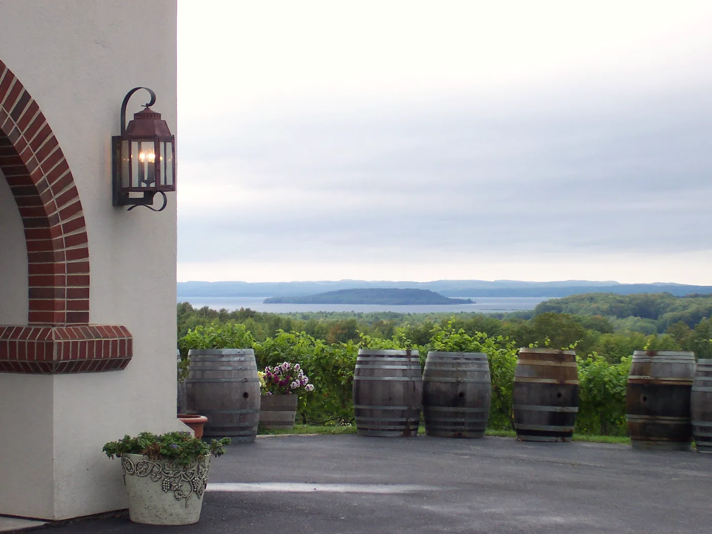 Oak wine barrels lined along the terrace at Chateau Chantal on Old Mission Peninsula, with vines and Grand Traverse Bay in the distance