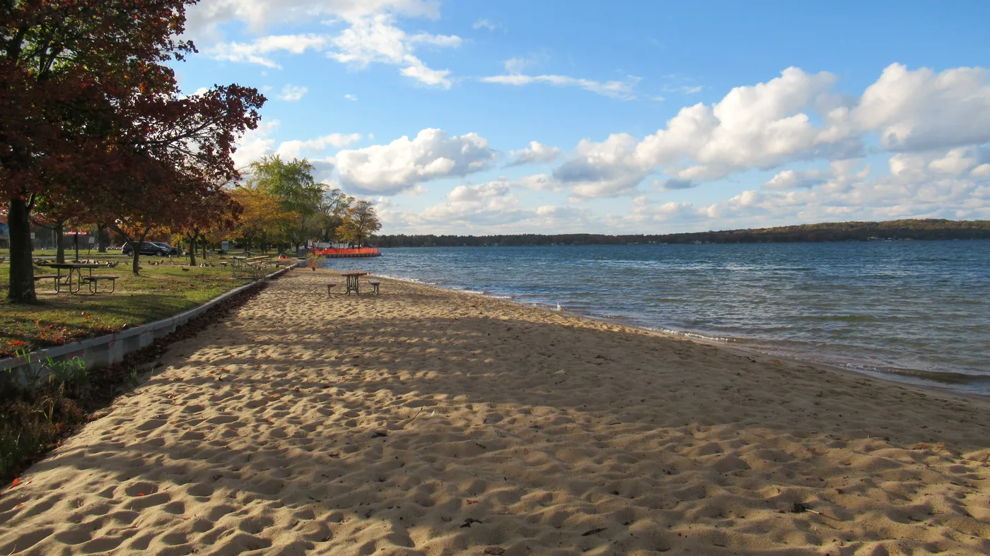 Sandy beach at Traverse City State Park on East Bay with calm blue water and wide shoreline
