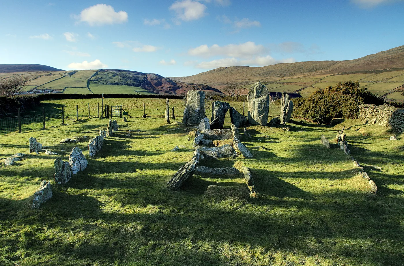 The bare standing stones and burial chambers of Cashtal yn Ard on a grassy hillside above Maughold