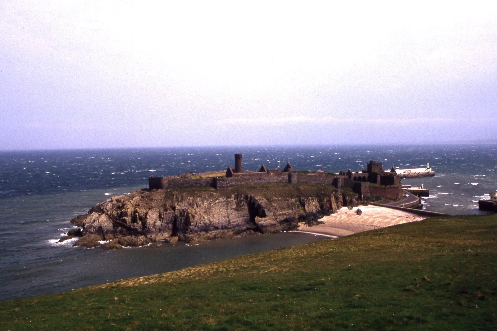 St Patrick's Isle at Peel, a rocky islet ringed by castle walls with a round tower, joined to the harbour by a causeway
