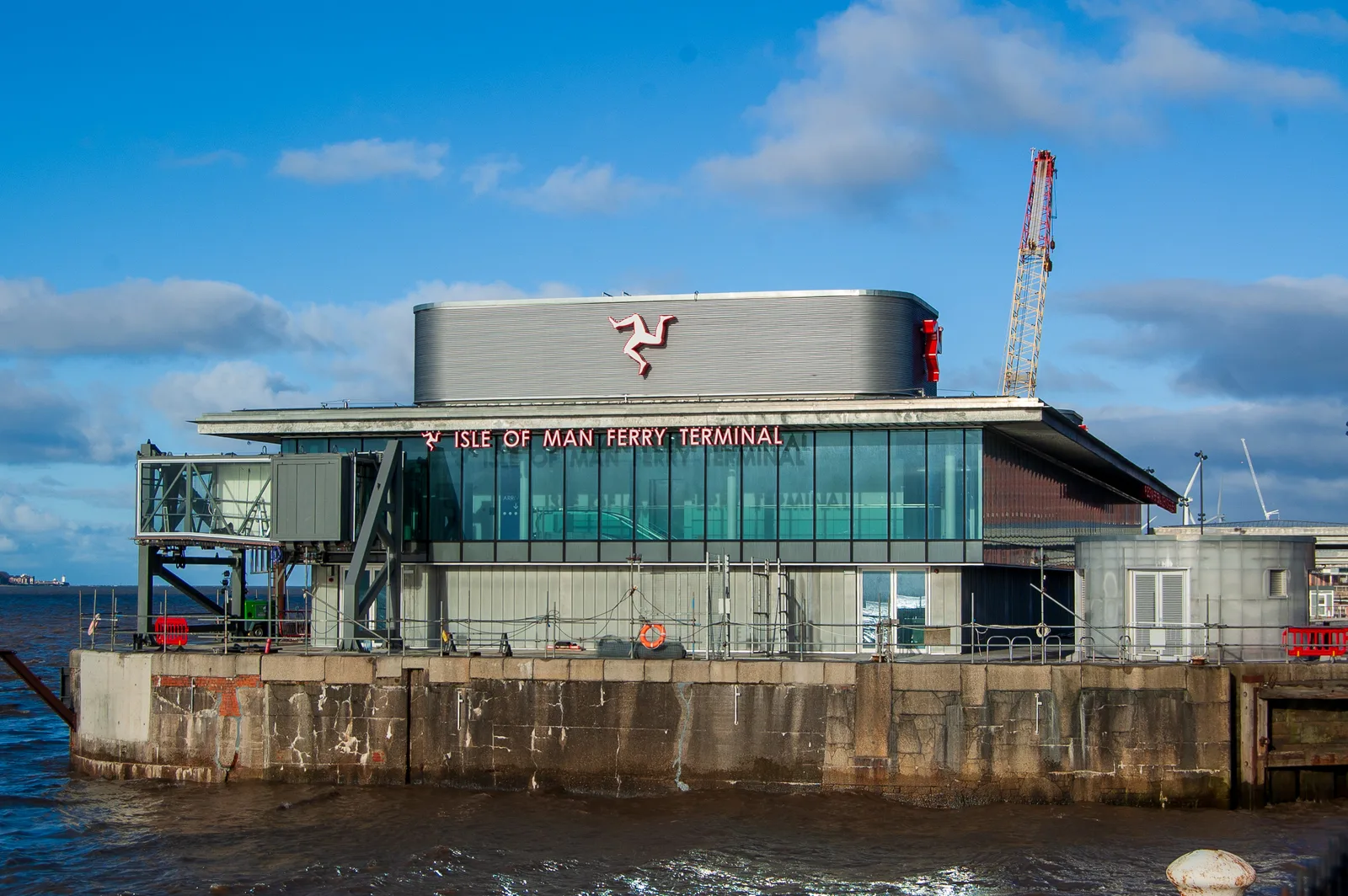 The glass-fronted Isle of Man Ferry Terminal on the Liverpool waterfront, with the three legs of Man on its roof