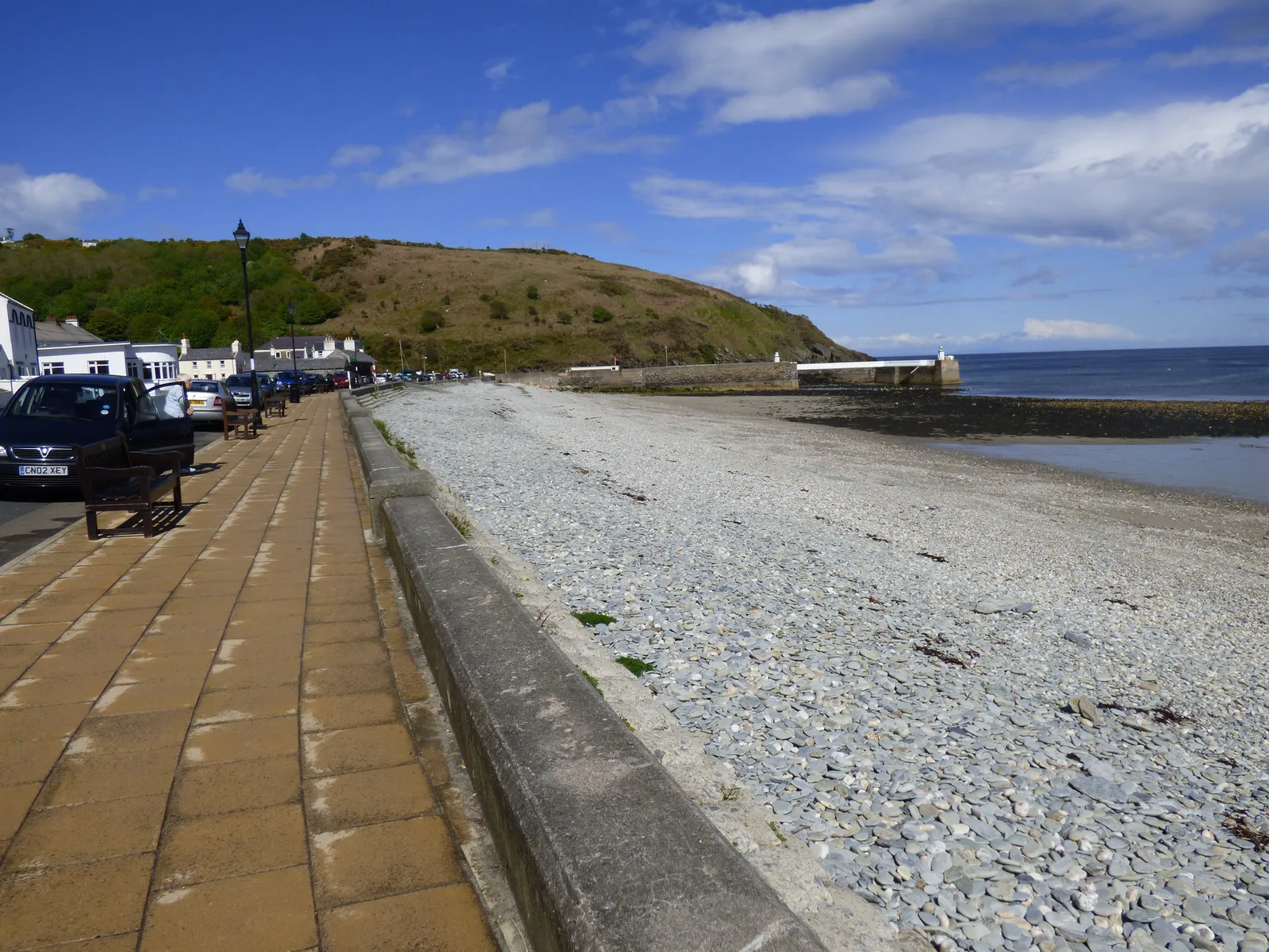 The pebble beach and promenade at Old Laxey running towards the harbour entrance