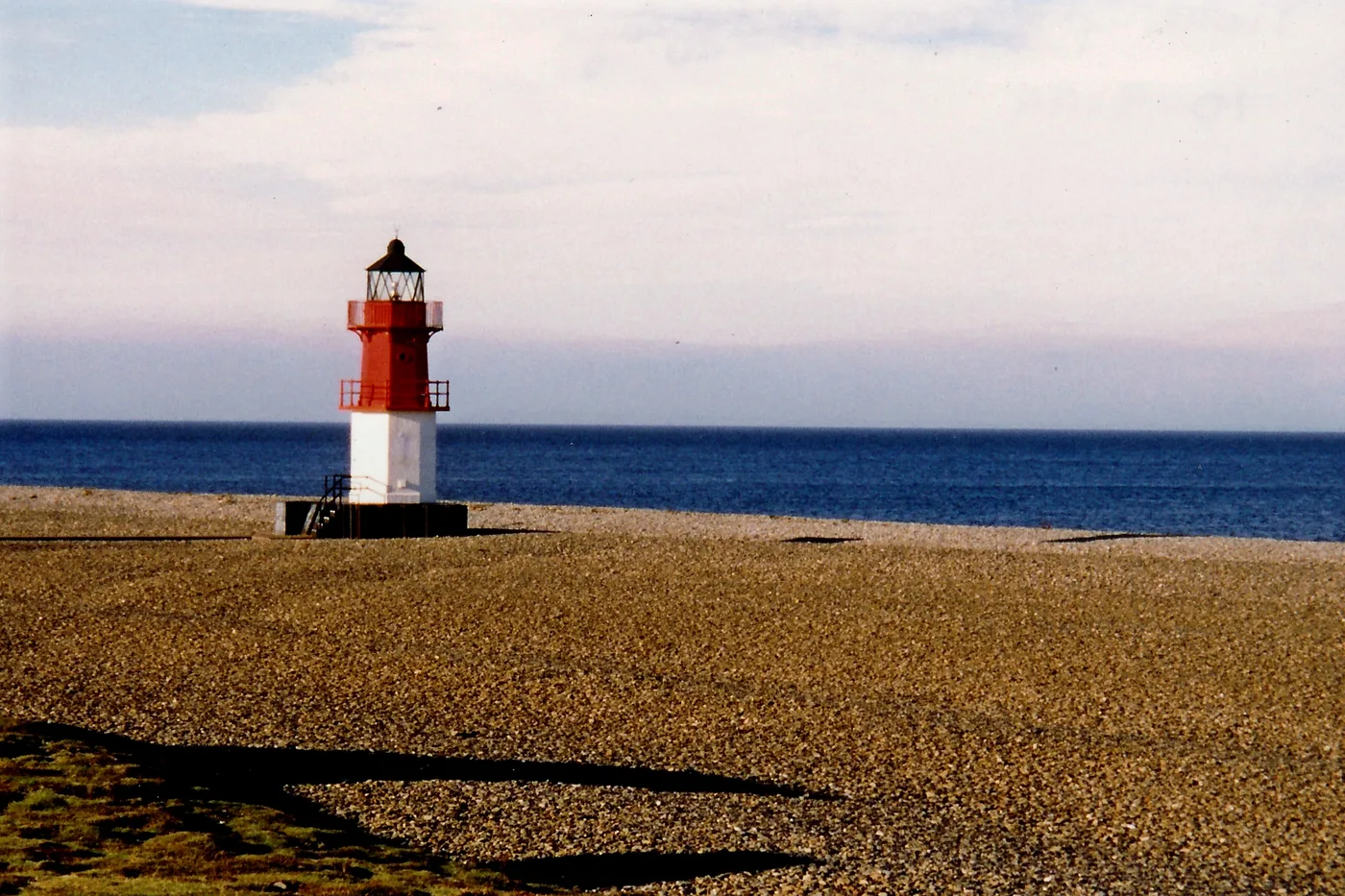 The shingle and gravel shore at the Point of Ayre at the northern tip of the Isle of Man, with a navigation beacon