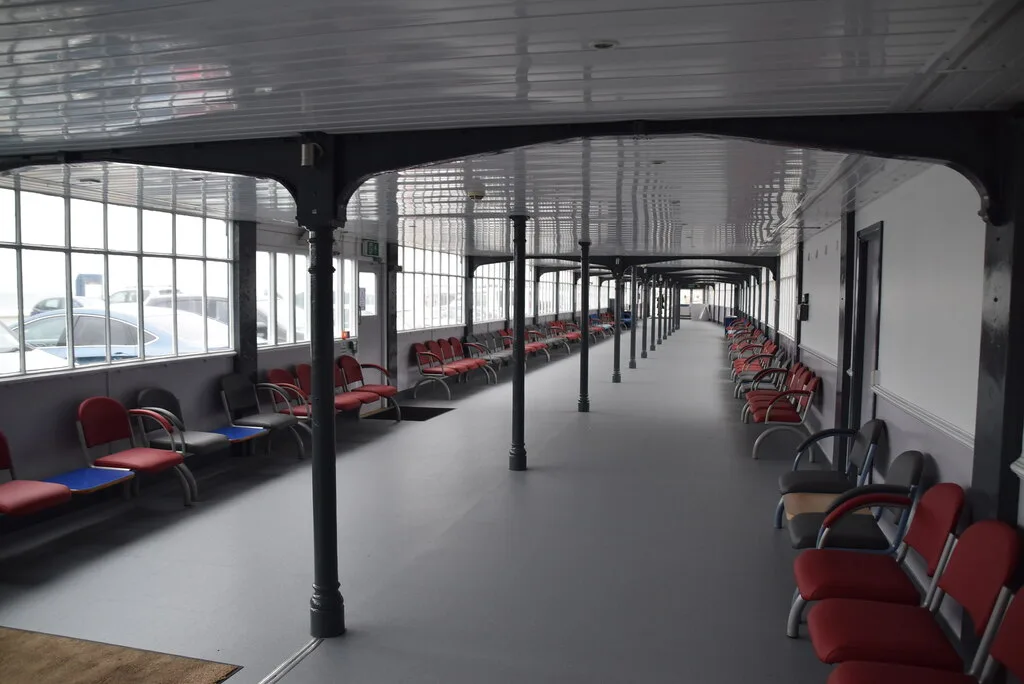 The covered waiting concourse inside the Sea Terminal in Douglas, rows of red seating under an arched roof