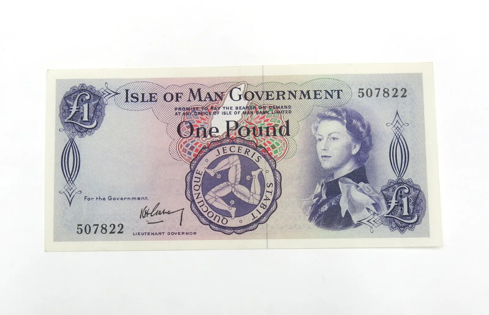 An Isle of Man Government one-pound note in blue and purple, with the three-legged Manx emblem and a portrait of the young Queen Elizabeth II