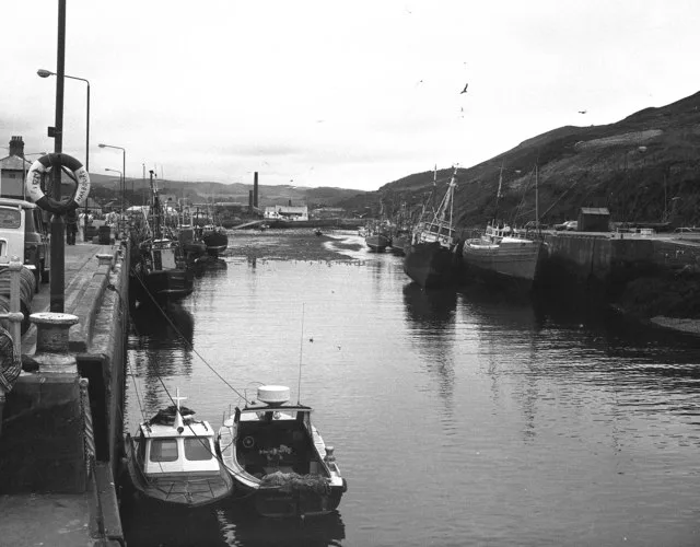 Peel Harbour at low tide with a former herring smokery chimney at the head of the harbour