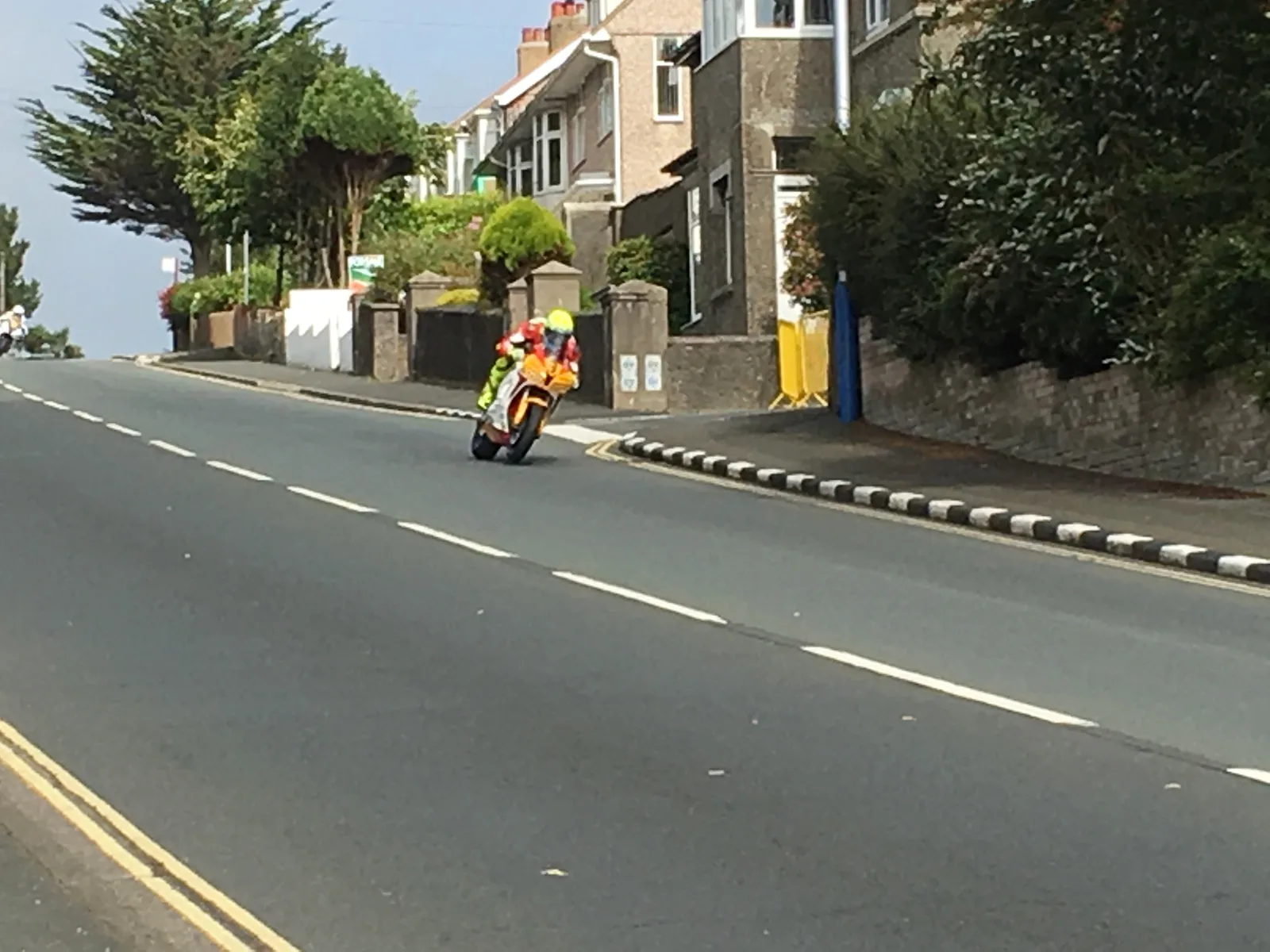 A competitor leaning a motorcycle into a bend on a residential stretch of the course during the Manx Grand Prix