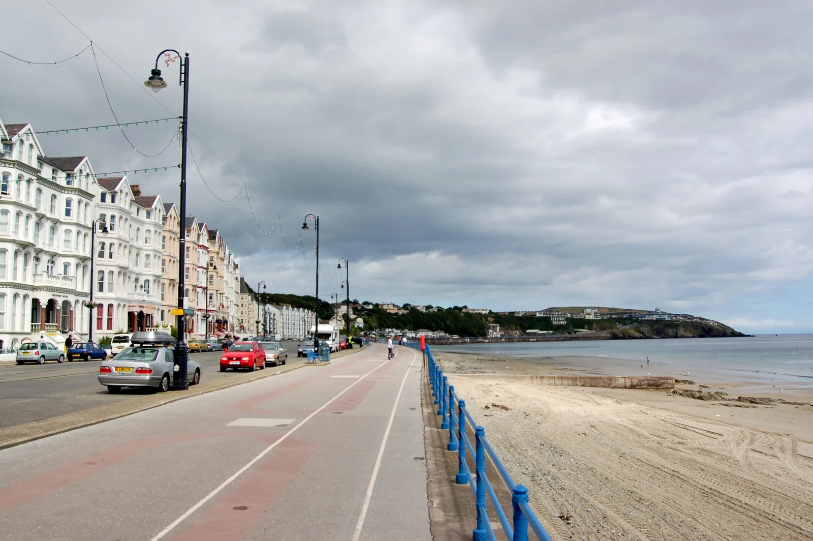 A long terrace of white hotels on Queens Promenade in Douglas, with the promenade and beach of Douglas Bay beside it