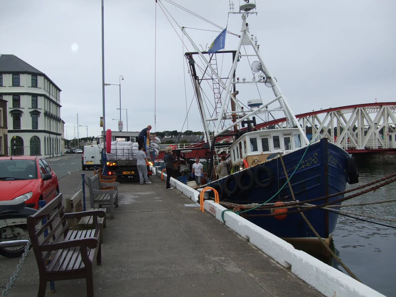 Sacks of queenies being lifted from a fishing boat onto a lorry on the quay at Ramsey harbour
