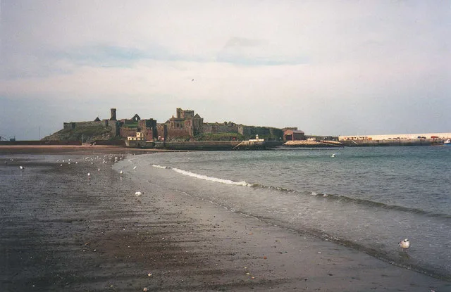 St Patrick's Isle and Peel Castle seen at low tide from the beach, with the harbour jetty running off to the right
