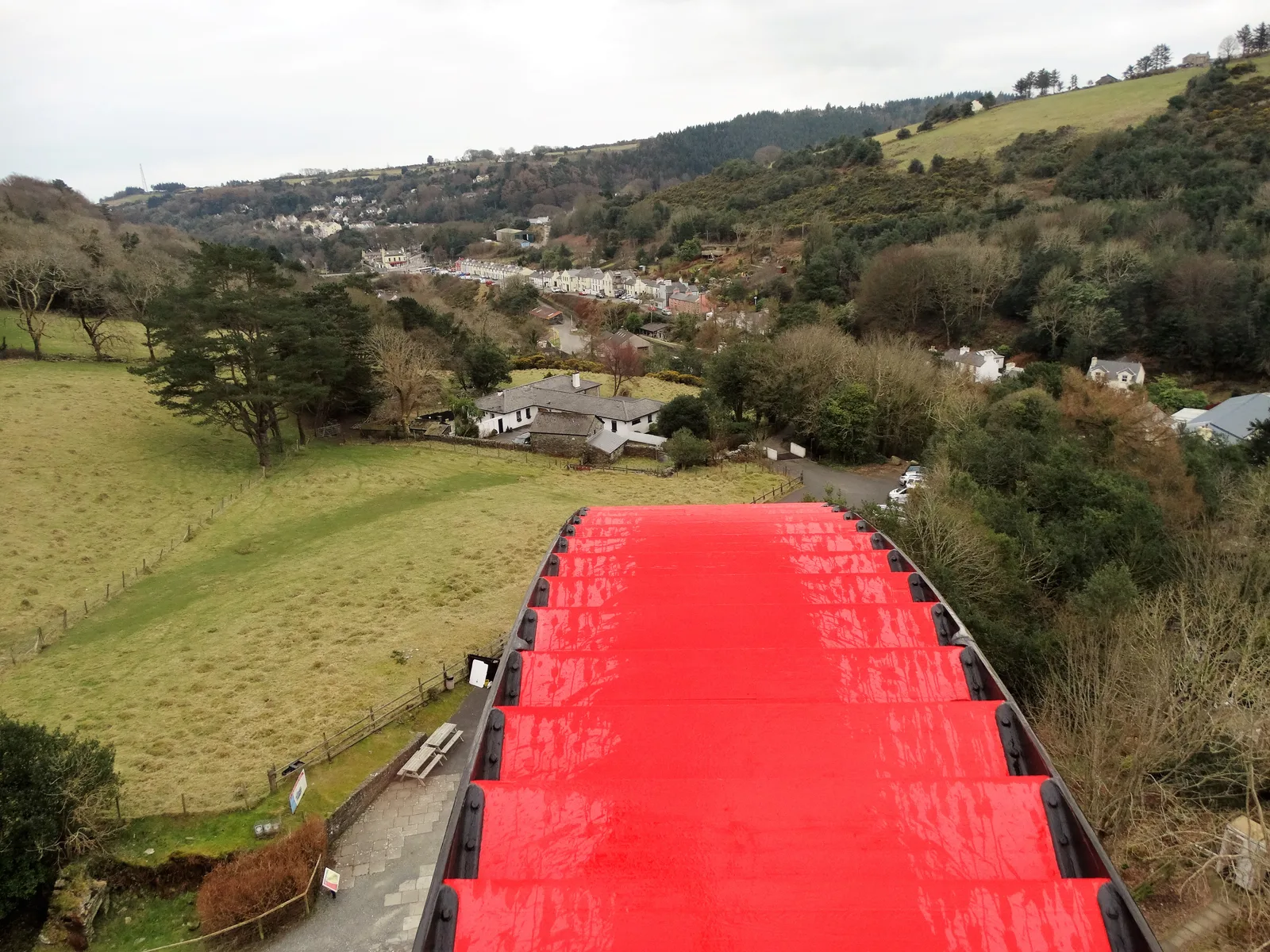 Looking down over the red rim of the Great Laxey Wheel from the viewing platform, towards the houses of Laxey