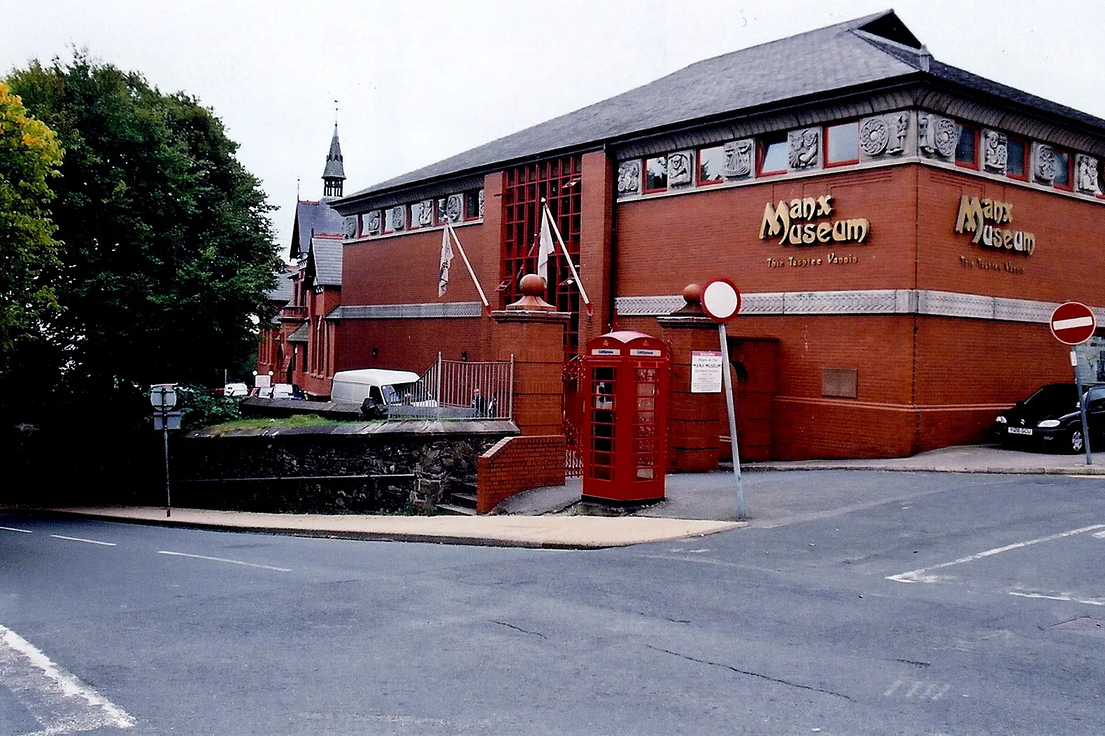 The red-brick Manx Museum building in Douglas with its gold lettering and a red telephone box outside