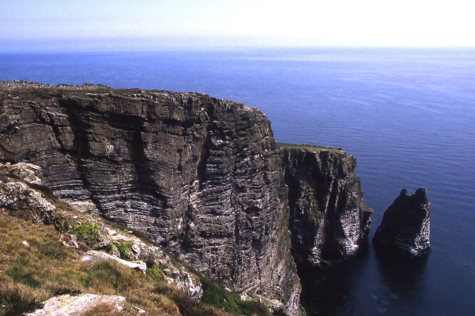 Layered sea cliffs at the Chasms with the Sugar Loaf sea stack standing offshore