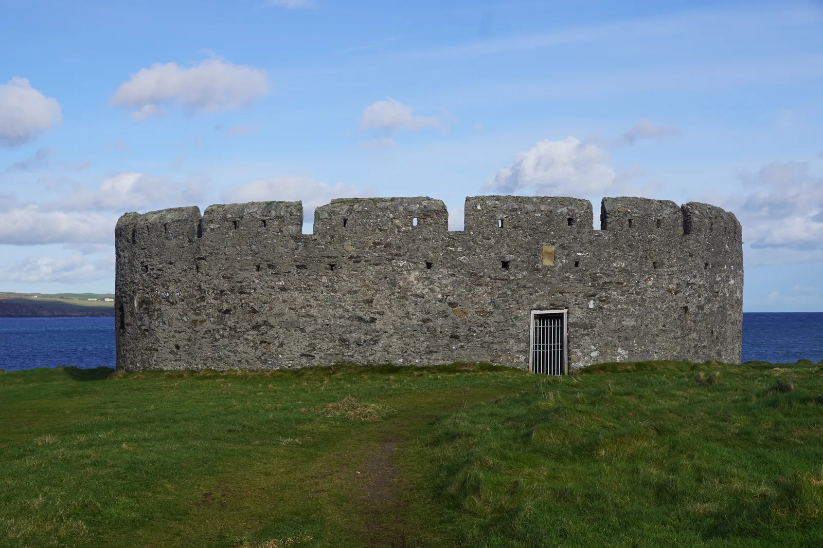 The round stone walls of Derby Fort on the grass of St Michael's Isle