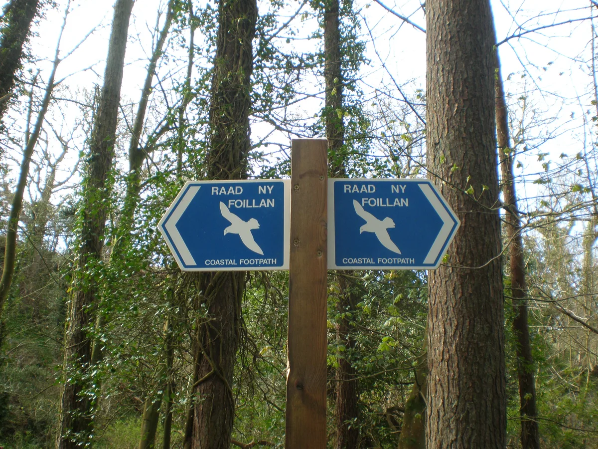 A wooden Raad ny Foillan signpost carrying the gull waymark that marks the Isle of Man coastal path