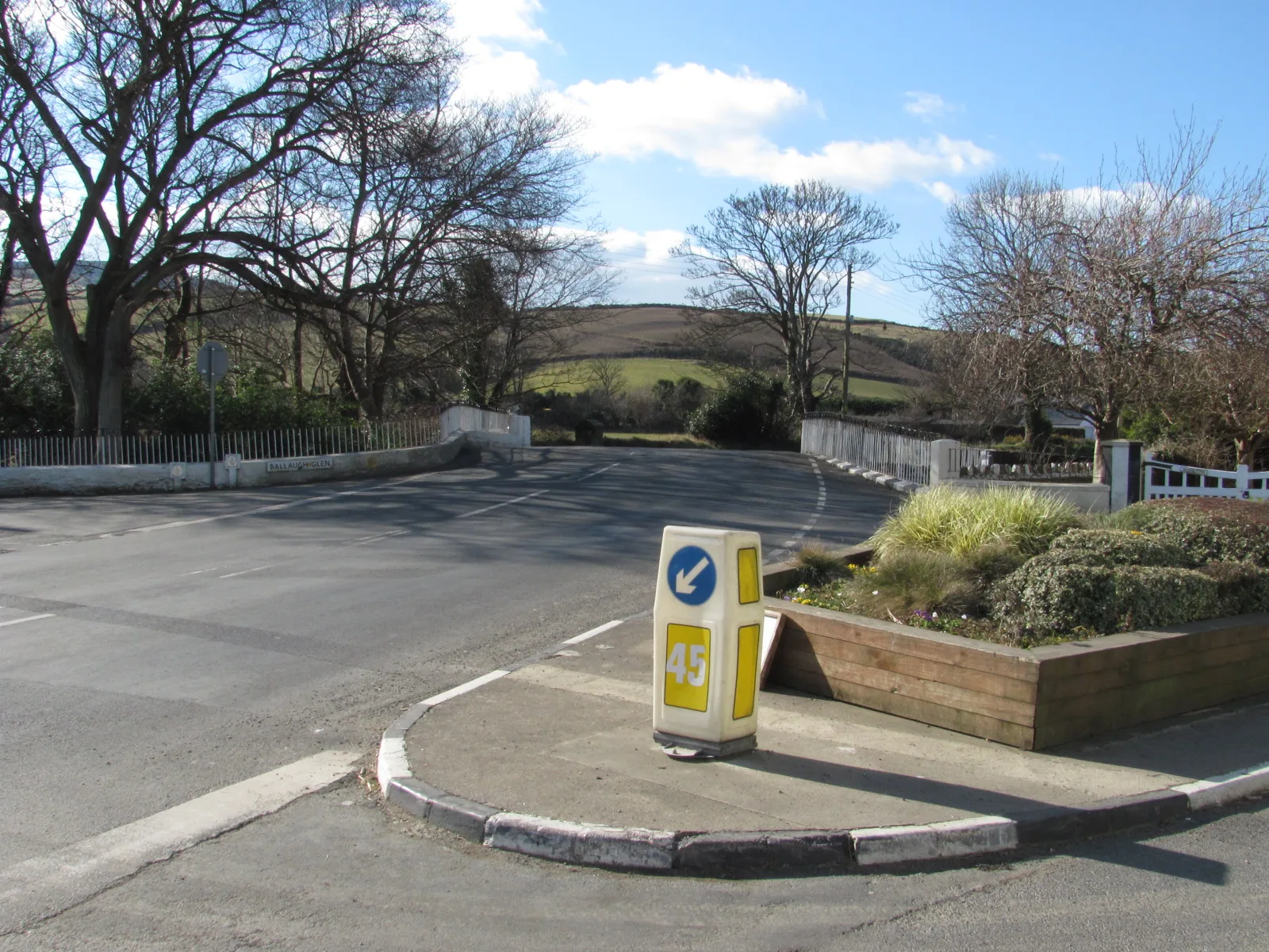 The humpbacked Ballaugh Bridge on the A3, with white railings on both sides and hills beyond, on an open-road day