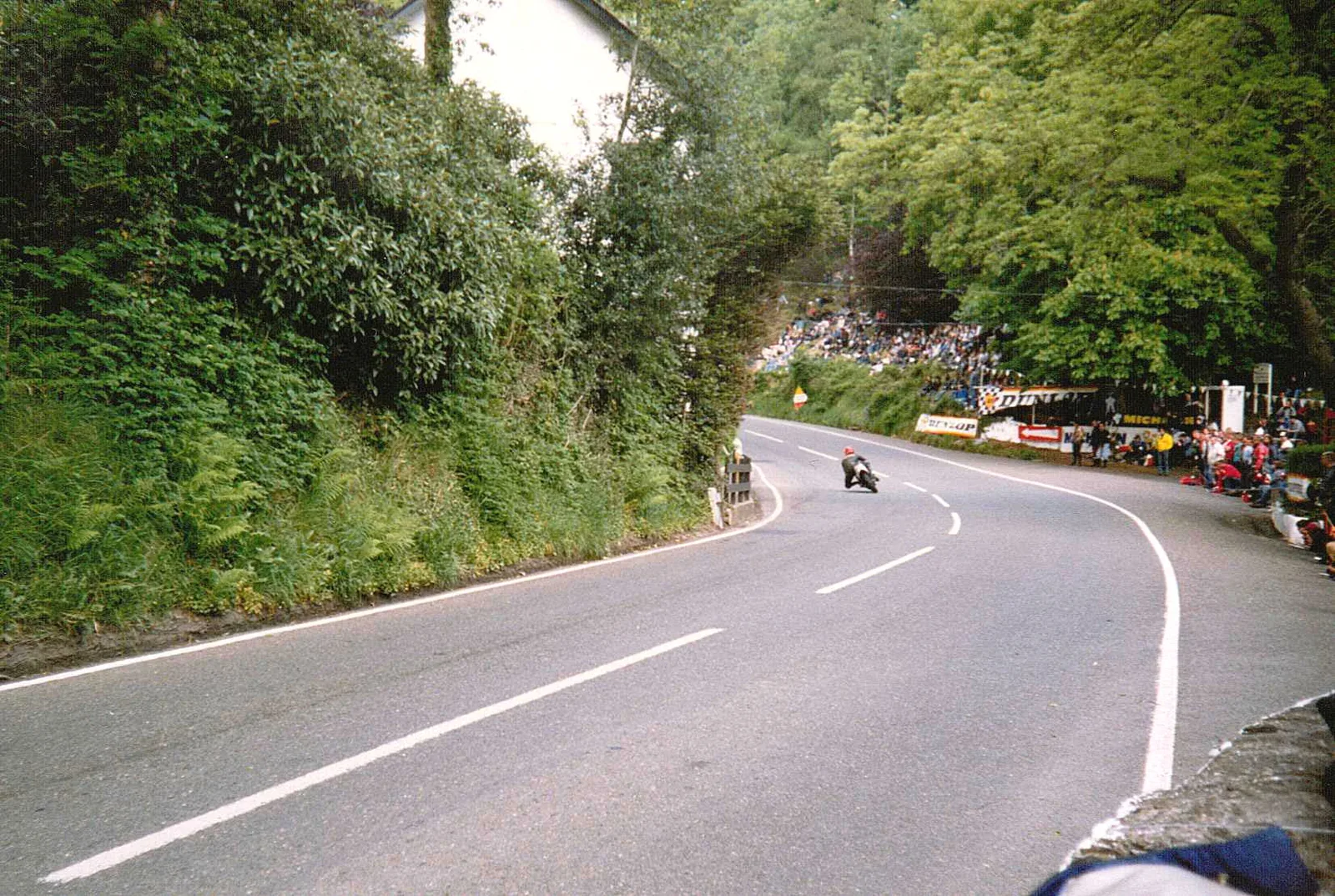 Spectators packed along the banks and walls at Glen Helen as a motorcycle takes the left-hand bend on the Snaefell Mountain Course