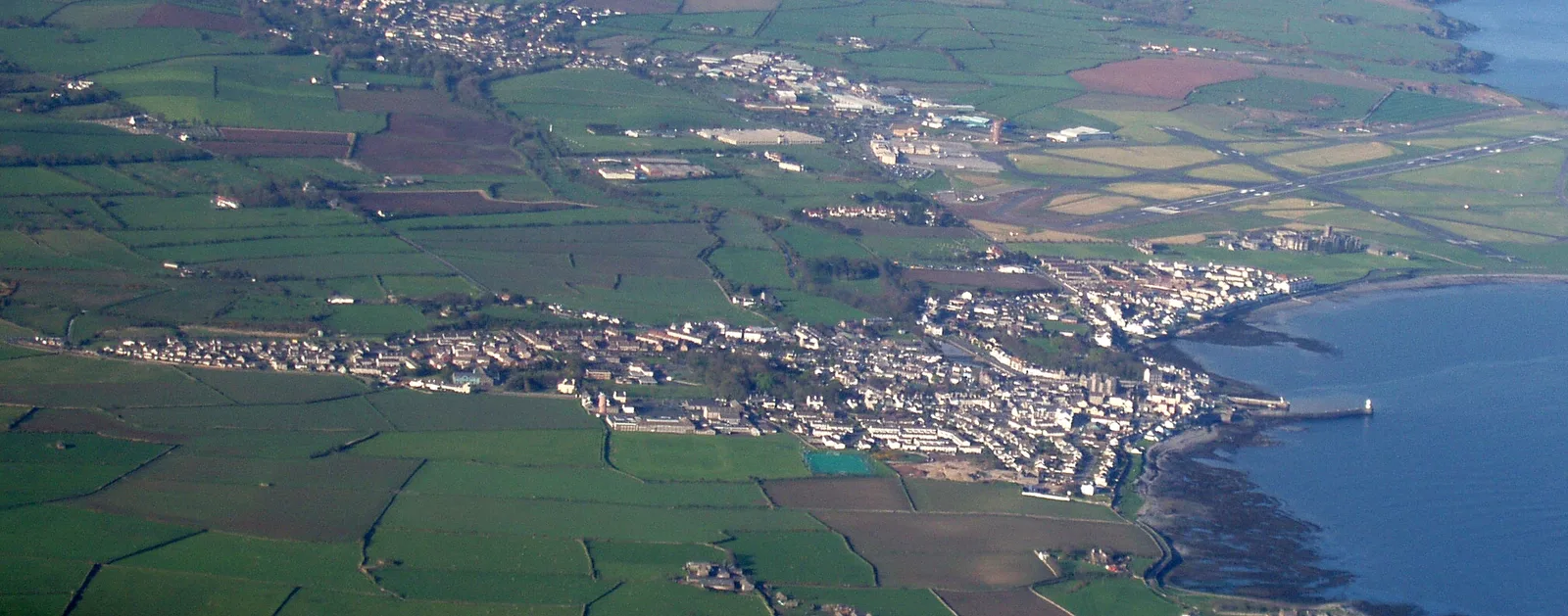 Aerial view of Castletown on the south coast with the coastline running away towards Douglas Head