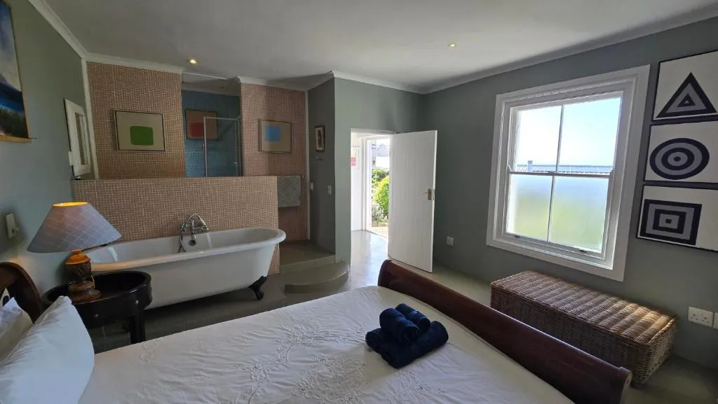Bedroom with an open-plan tub, sash window and colourful geometric artwork