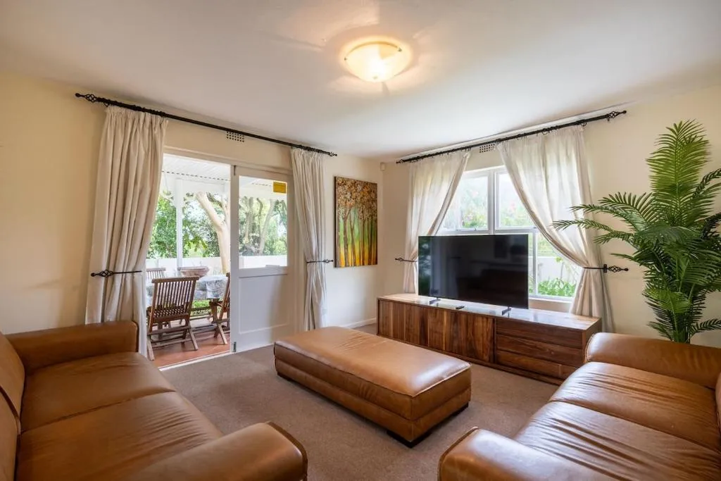 Living room with leather sofas, a wood-topped TV console, and glass doors to the porch