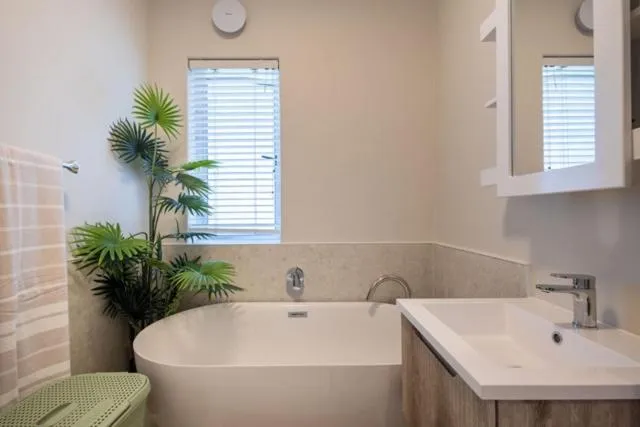 Bathroom with a freestanding tub, potted palm and marble-tiled surround