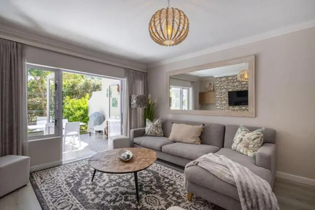 Living room with a grey sectional sofa, round chandelier and doors opening onto the patio