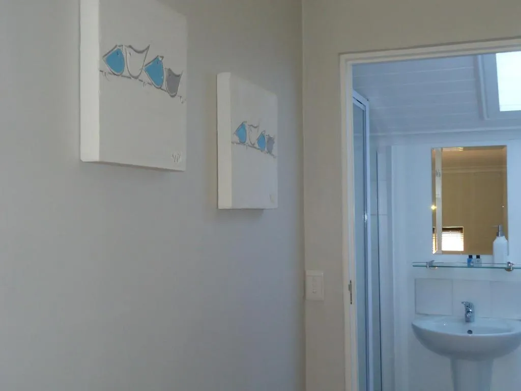 Hallway with framed coastal artwork leading through to the en-suite bathroom