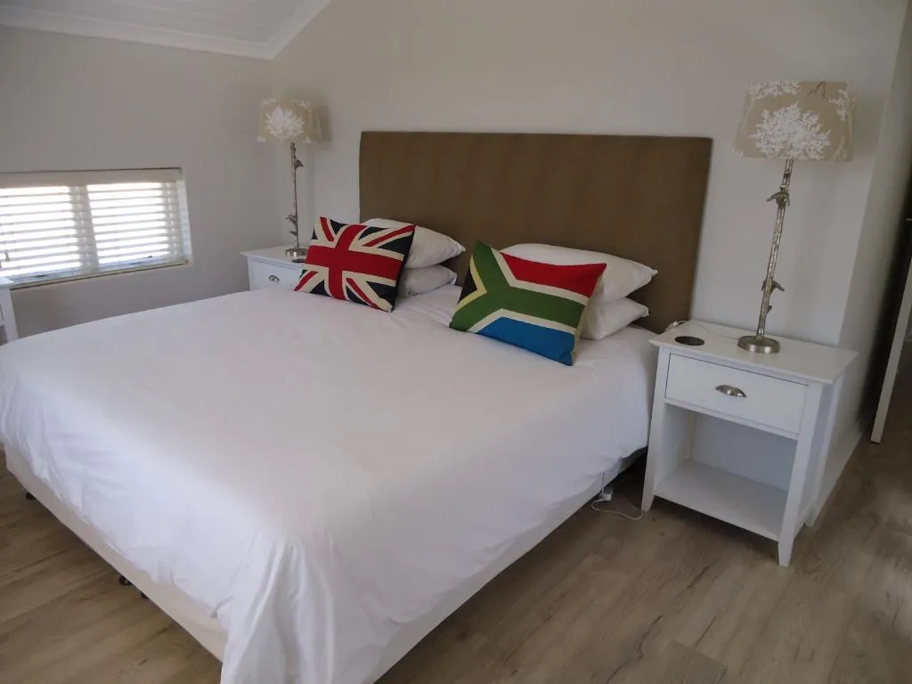 King bedroom with Union Jack and South African flag scatter cushions on white bedding