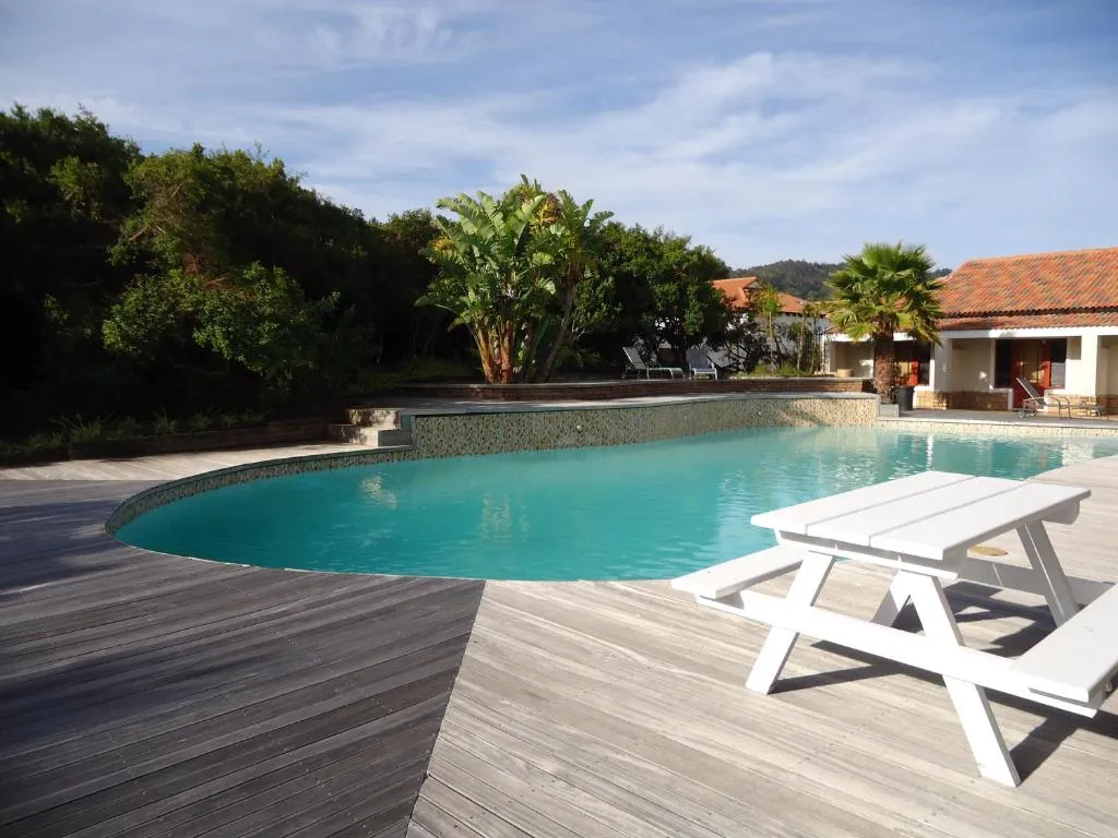 Shared estate swimming pool with picnic table and thatched-roof clubhouse buildings beyond