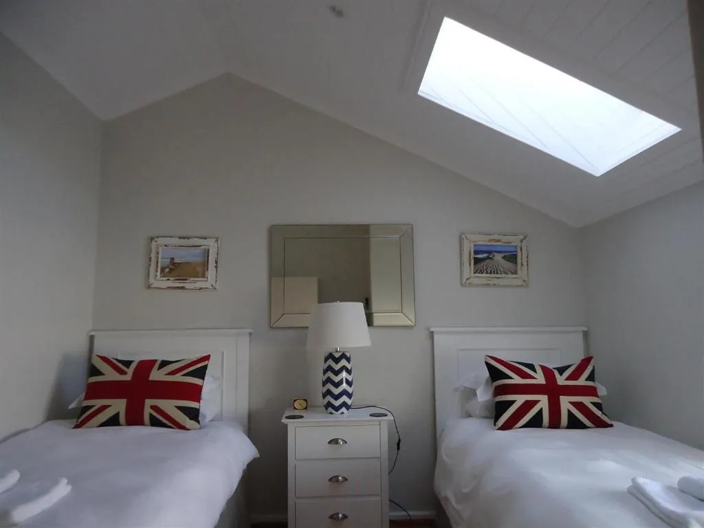 Twin bedroom with skylight, matching red-white-blue cushions and bedside mirror