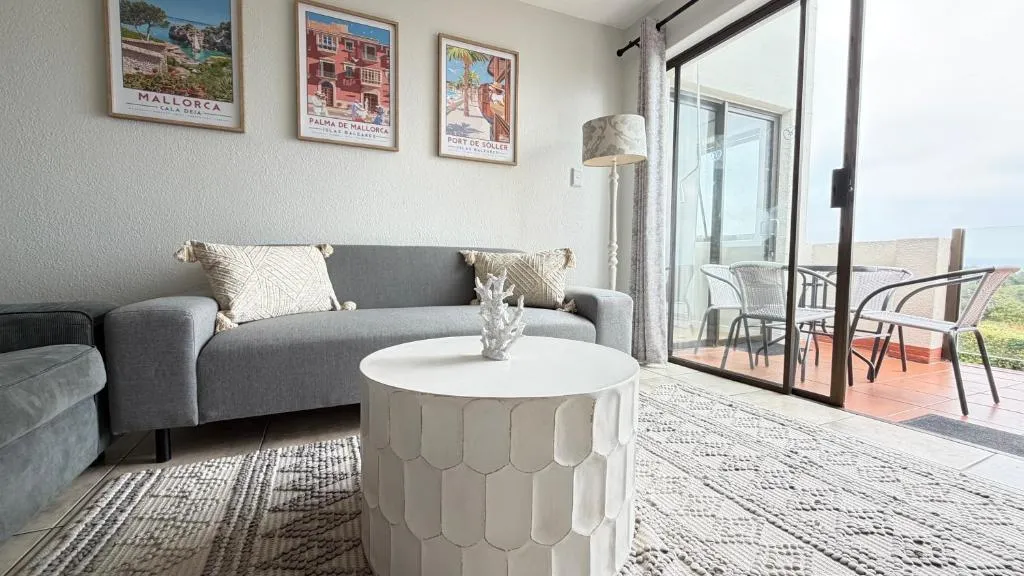 Bedroom with white linen, wood headboard and woven sun-disc wall decor