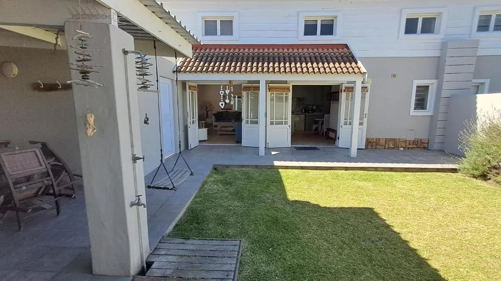 Paved back patio and lawn with French doors opening into the living and kitchen area