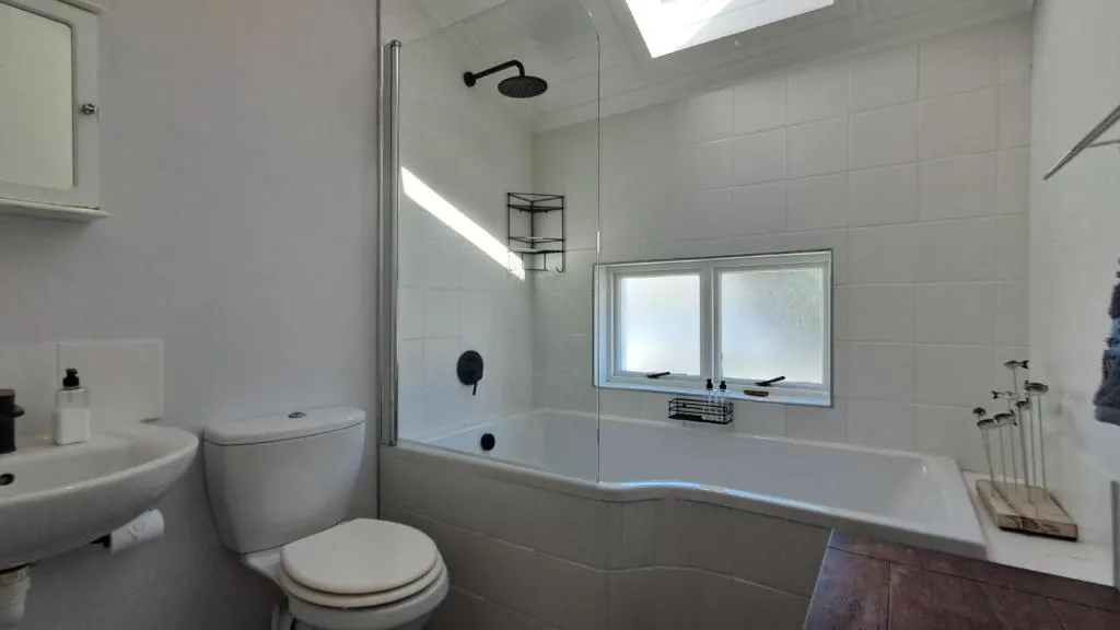 Family bathroom with corner bath, glass shower screen and frosted window