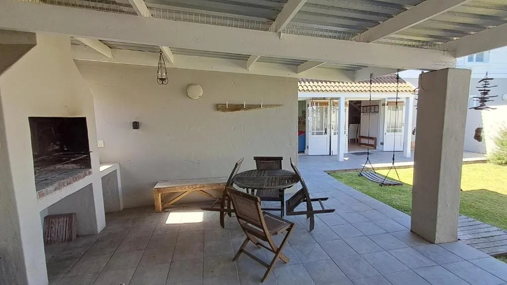 Covered patio with built-in brick braai, wooden table and chairs