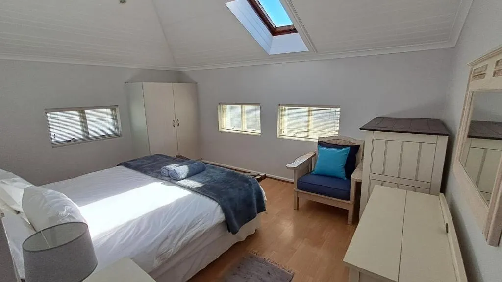 Loft-style bedroom with vaulted ceiling, skylight and double bed under sloped walls