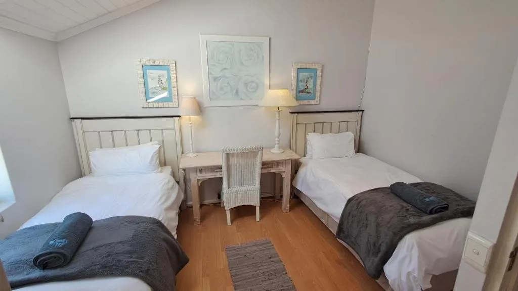 Twin bedroom with matching white headboards, bedside desk and reading lamps